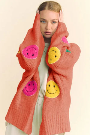 Person wearing a bright orange scarf with smiley face patterns on a beige background