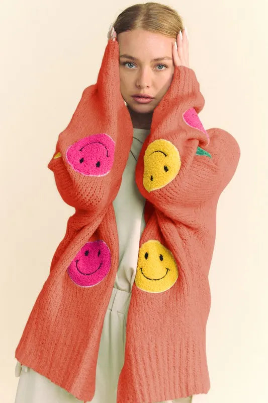 Person wearing a bright orange scarf with smiley face patterns on a beige background