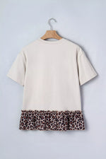 Beige t-shirt with leopard print hem on a hanger against a light gray background