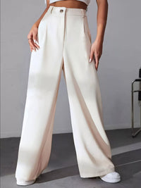 Person wearing white wide-leg pants on a gray background