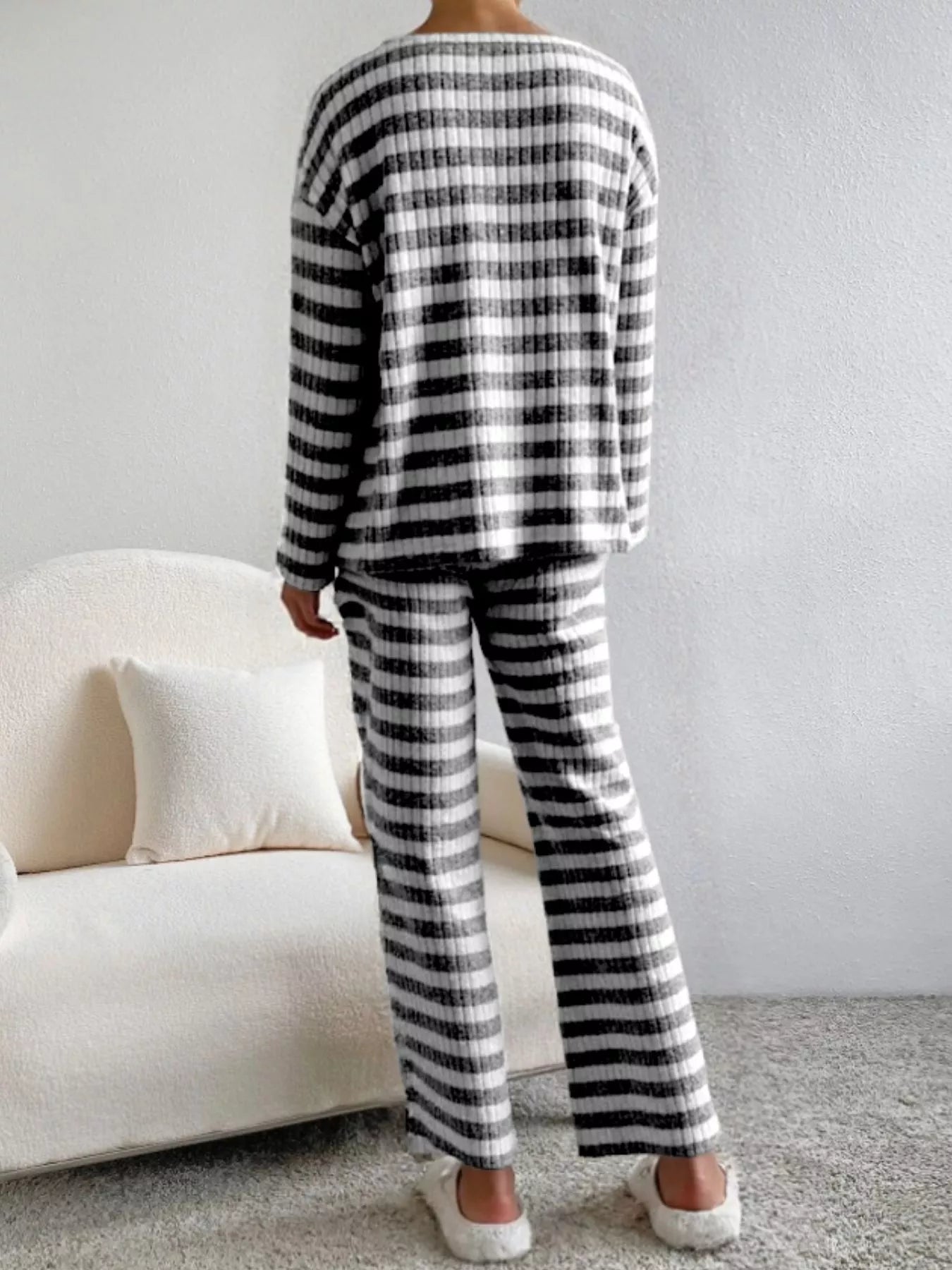 Person wearing a black and white striped outfit in a minimalistic room.