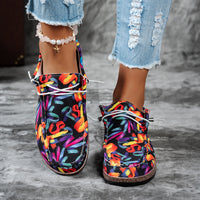 Colorful patterned shoes worn with ripped jeans on a gray surface