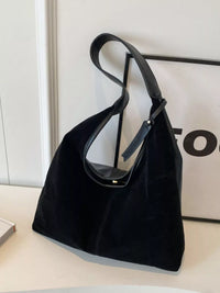 Black handbag on a light surface with a blurred background