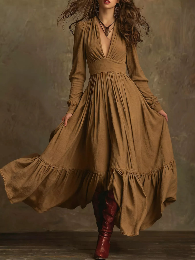 Woman wearing a long brown dress with a deep neckline and burgundy boots against a textured brown background.