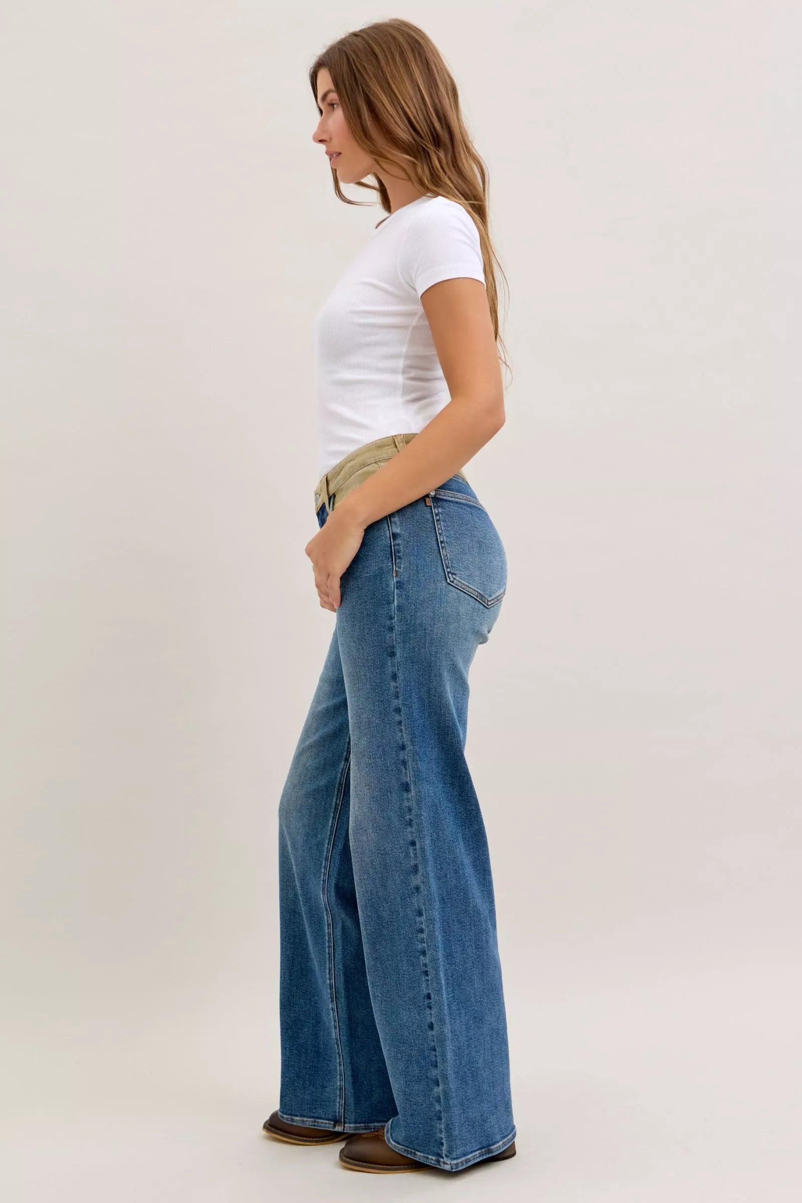 Woman wearing a white t-shirt and blue jeans on a plain background