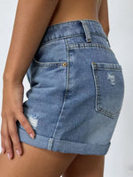 Blue denim shorts worn by a person on a white background