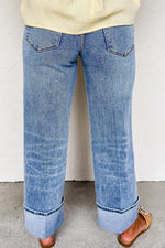 Blue jeans worn by a person on a plain background