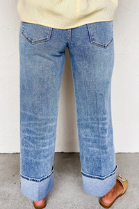 Blue jeans worn by a person on a plain background