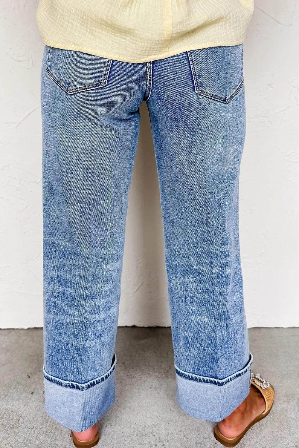 Blue jeans worn by a person on a plain background