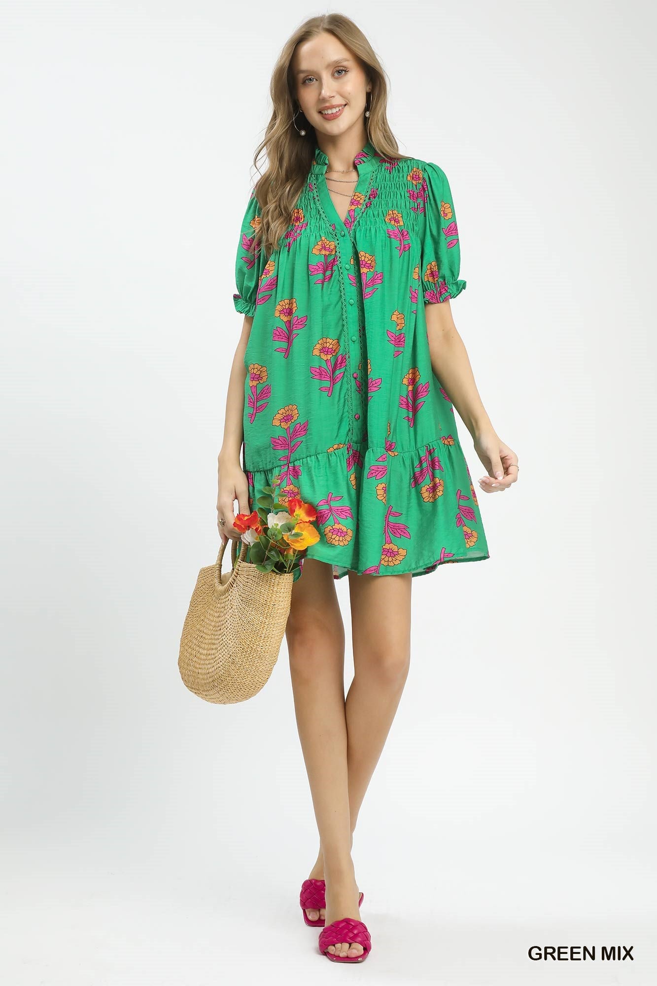 Woman wearing a green floral dress holding a straw bag on a white background