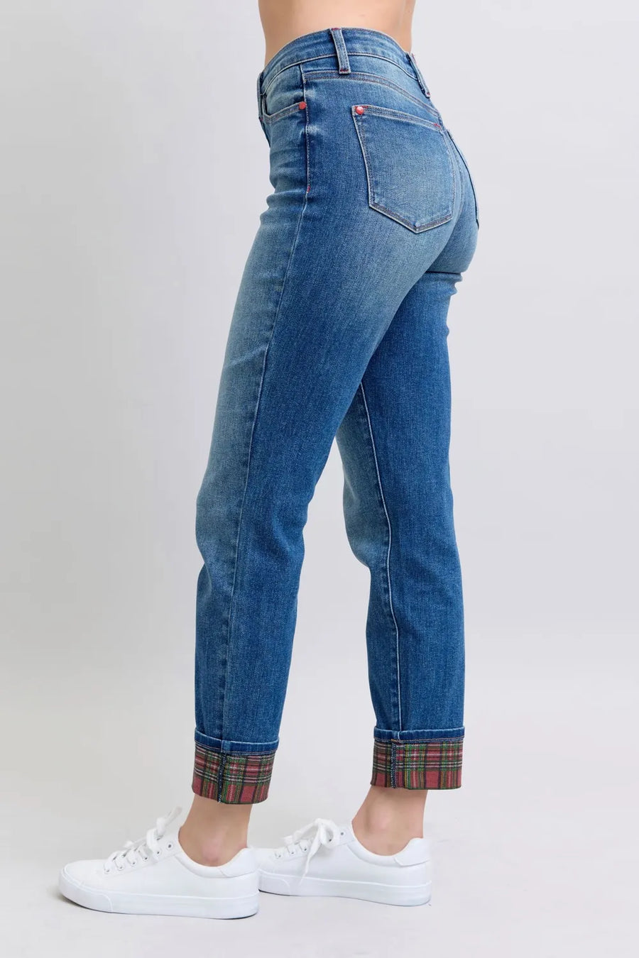 Blue jeans with plaid cuffs worn by a person on a light gray background