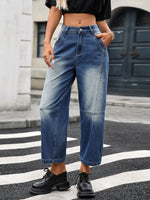Person wearing blue jeans and black shoes on a street.