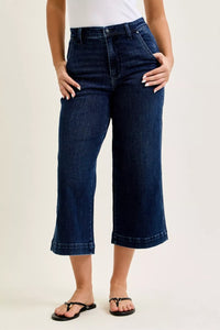 Person wearing dark blue jeans on a plain background