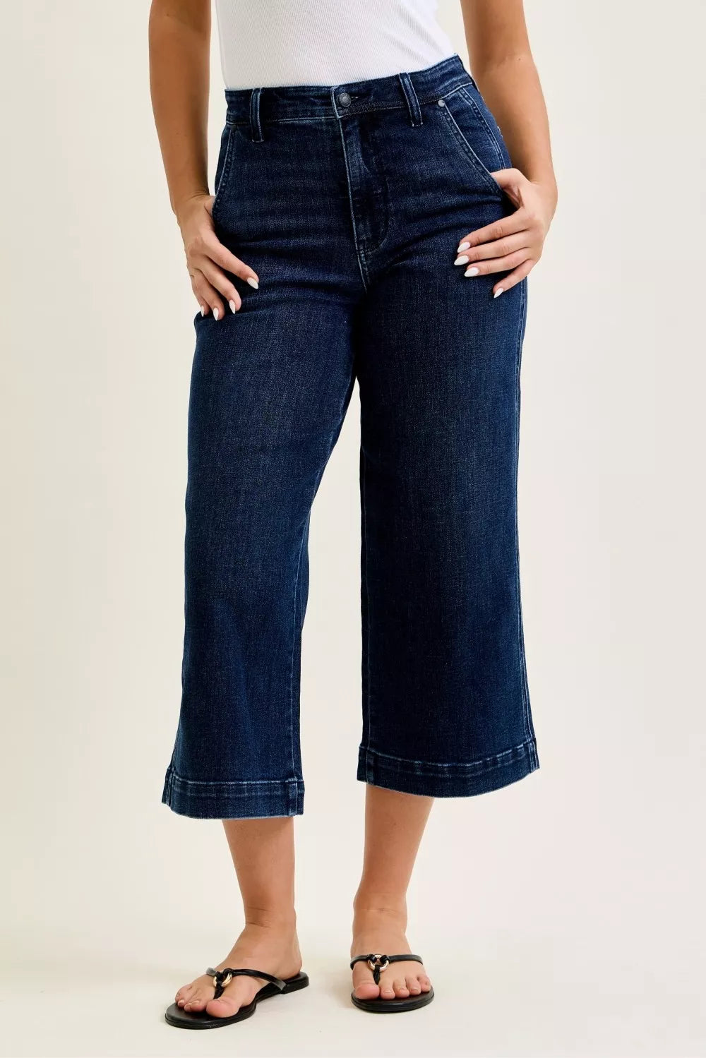 Person wearing dark blue jeans on a plain background