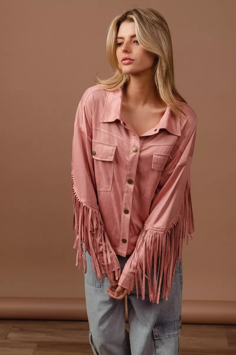 Woman wearing a pink fringed jacket against a brown background