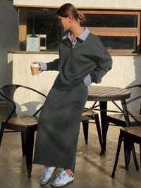 Woman in a gray outfit holding a coffee cup in an outdoor setting.