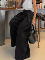 Person wearing black wide-leg pants and a white top in an indoor setting.
