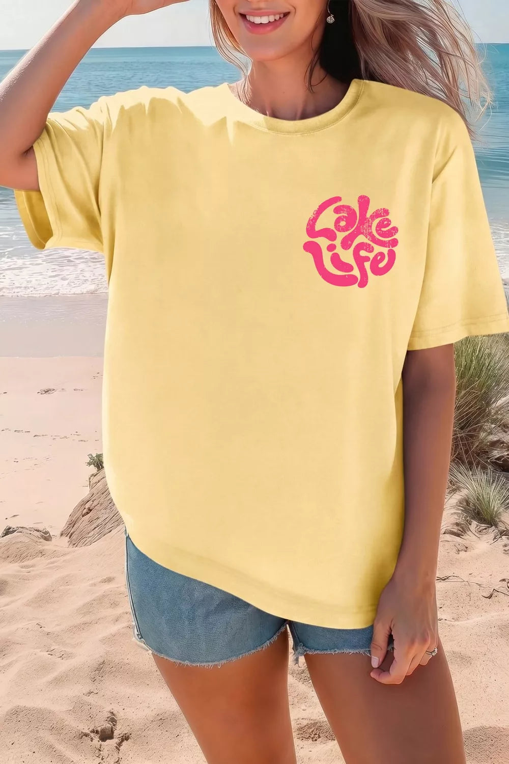 Person wearing a yellow t-shirt with 'Lake Life' design on a beach