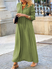 Woman wearing a green dress standing on a stone pavement.