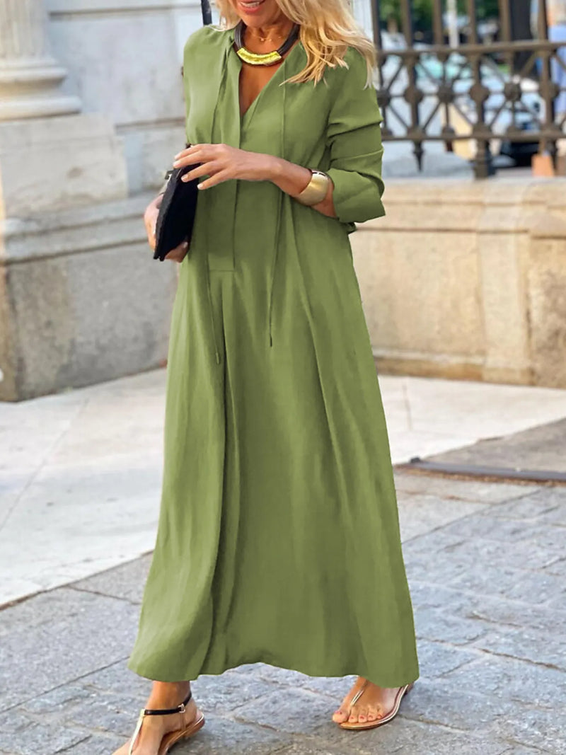 Woman wearing a green dress standing on a stone pavement.