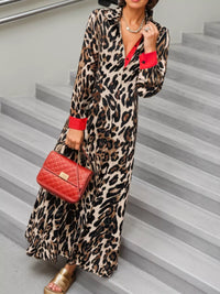 Person wearing a leopard print dress with red accents and holding a red handbag on stairs.