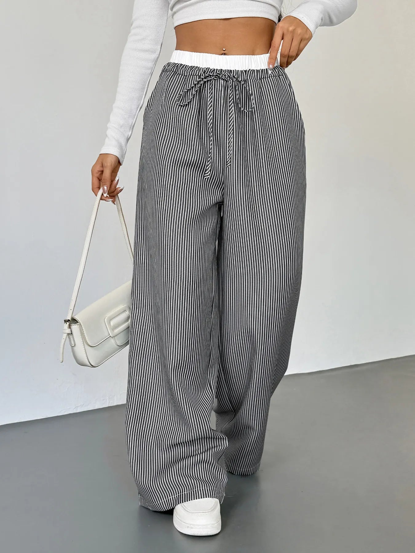 Person wearing gray and white striped pants with a white background