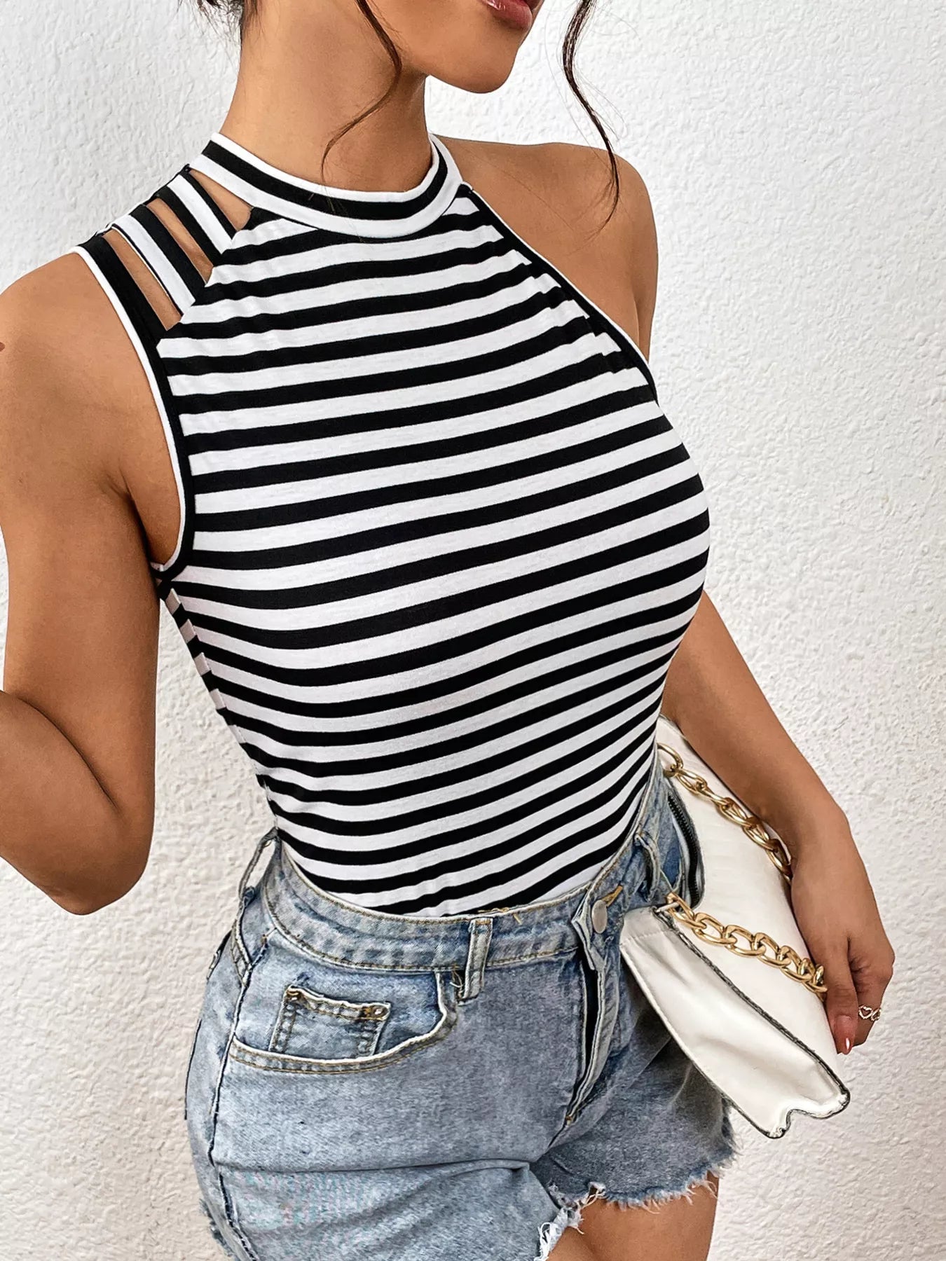 Person wearing a black and white striped tank top and denim shorts against a white background
