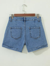 Blue denim shorts on a hanger against a white background