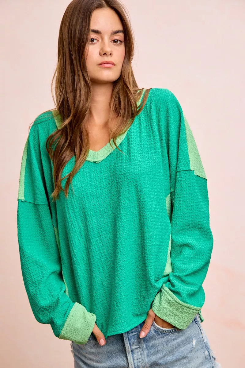 Woman wearing a green sweater with a plain background