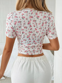 Person wearing a floral crop top and white pants in a minimal indoor setting