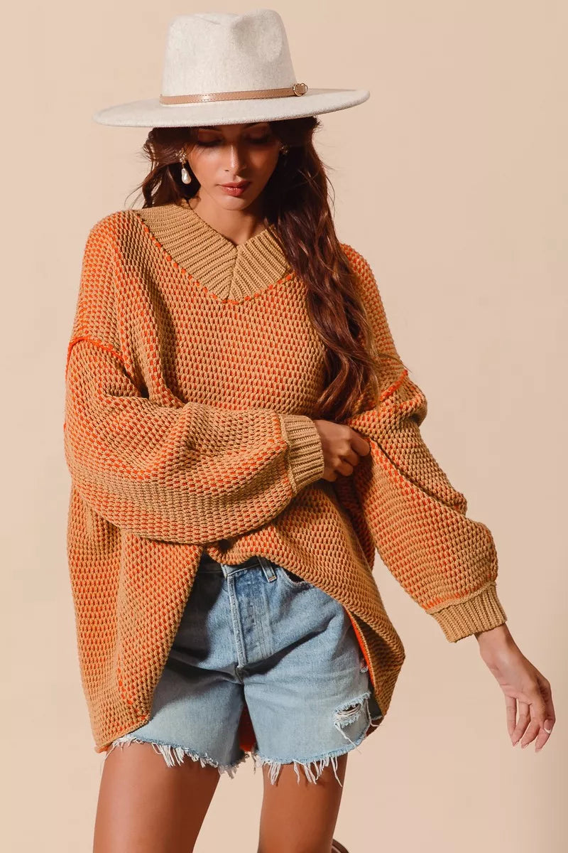 Woman wearing a mustard yellow sweater and denim shorts against a beige background