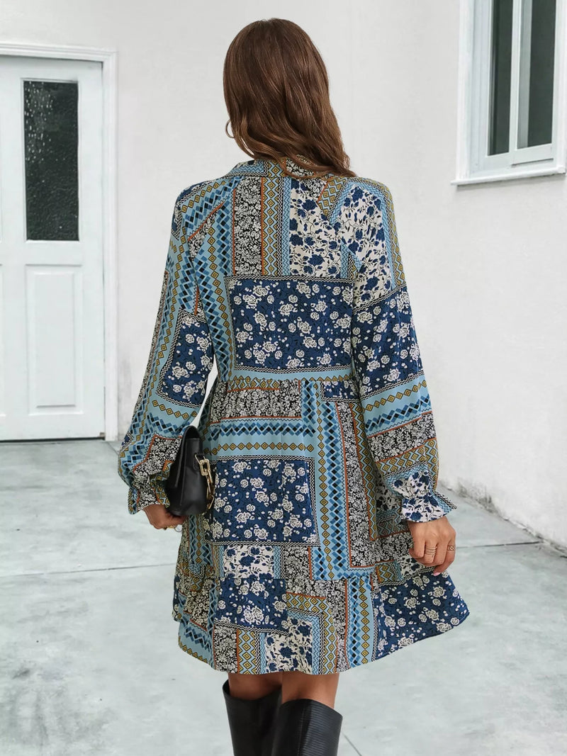 Woman wearing a patterned dress standing in a room with a white door and window.