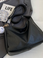 Black handbag with a 'LIFE' magazine and clear glass on a white surface