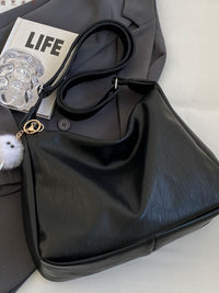 Black handbag with a 'LIFE' magazine and clear glass on a white surface