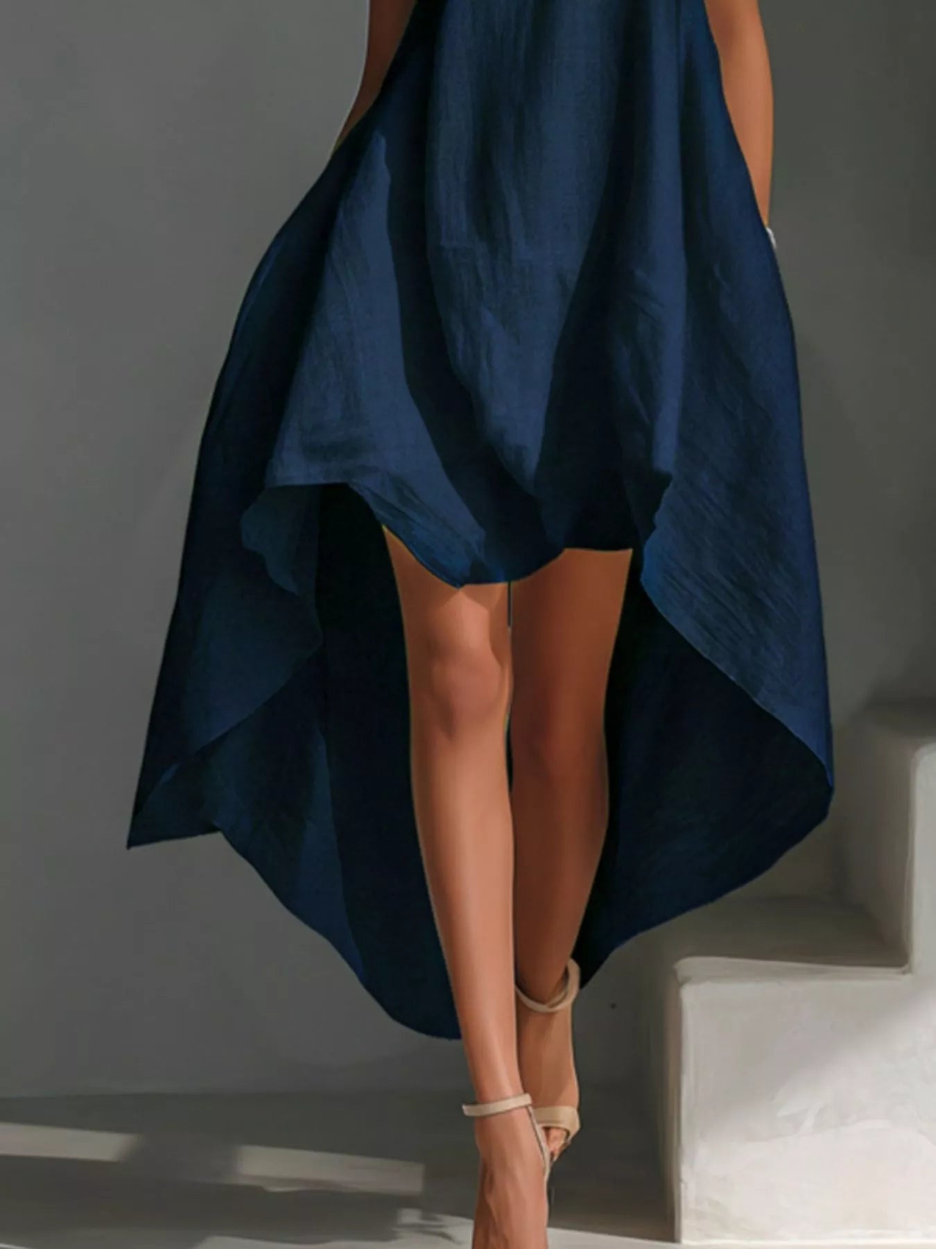 Navy blue dress with a high-low hem on a gray background