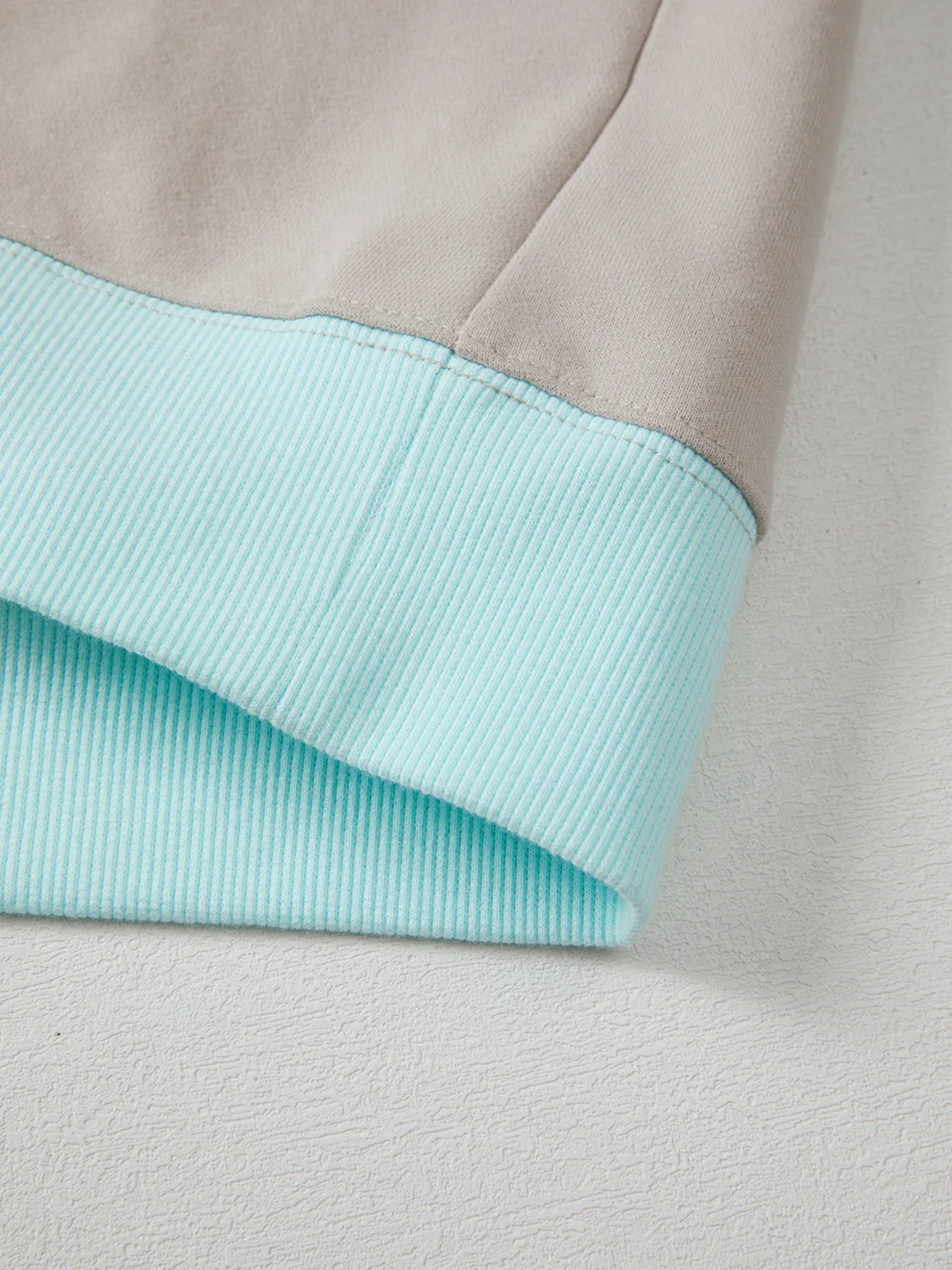 Close-up of a fabric with a light blue inner lining and gray outer layer.