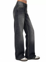 A side profile view of a person wearing dark gray wide-leg denim jeans and gray sneakers, shown against a plain white background.