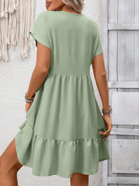 Green dress worn by a person against a light gray wooden panel background