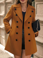 Person wearing a mustard yellow coat with black buttons on a street.
