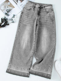 Gray jeans on a white surface with a magazine and flowers in the background