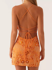 Orange dress with intricate detailing and thin straps on a plain background