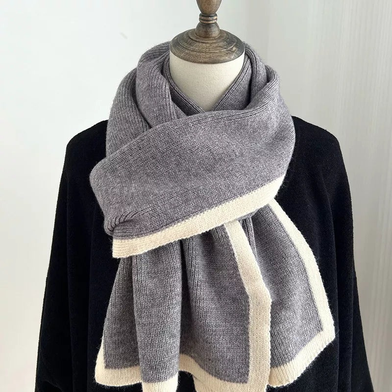 Gray scarf with white trim draped over a black garment on a mannequin against a white background