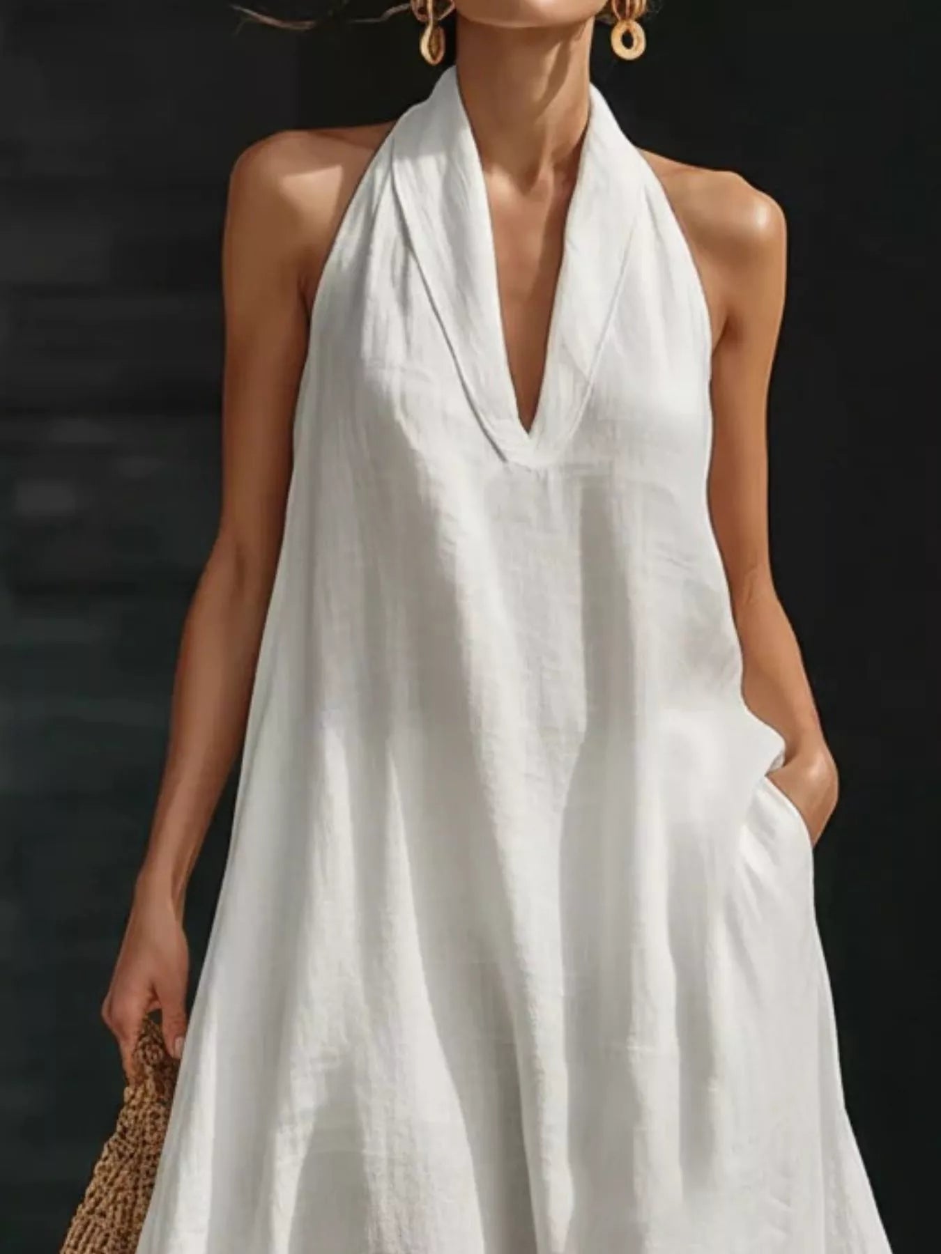 Woman wearing a white halter neck dress against a dark background