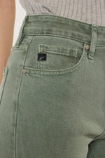 Close-up of green jeans with a brand logo on the pocket.