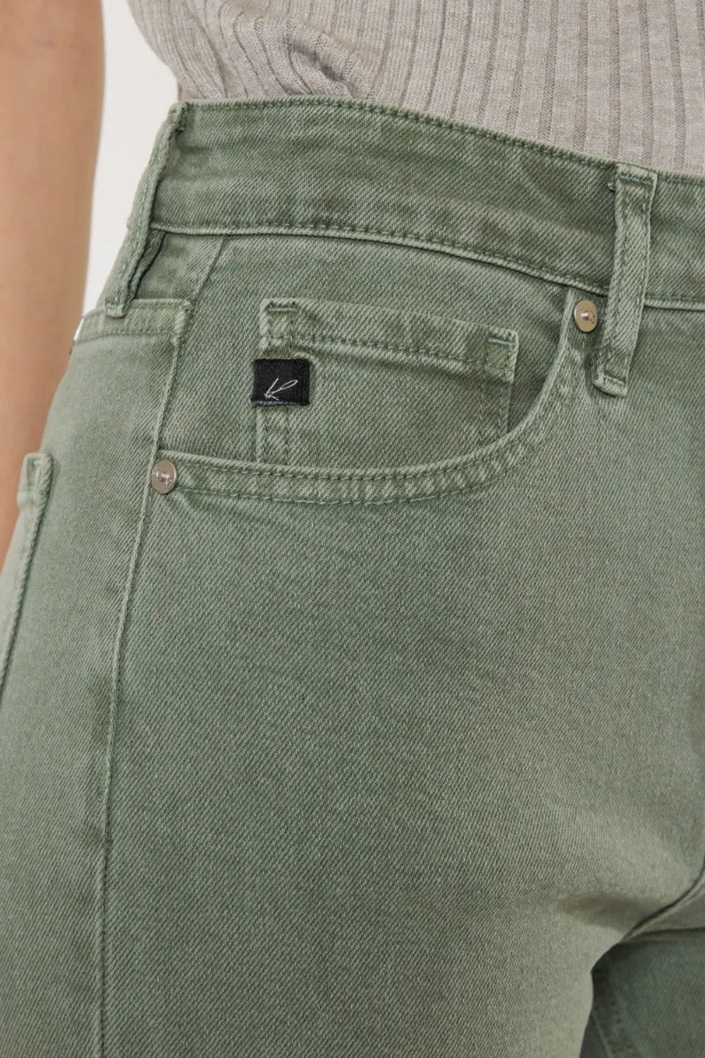 Close-up of green jeans with a brand logo on the pocket.