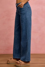 Person wearing blue jeans with a pink background