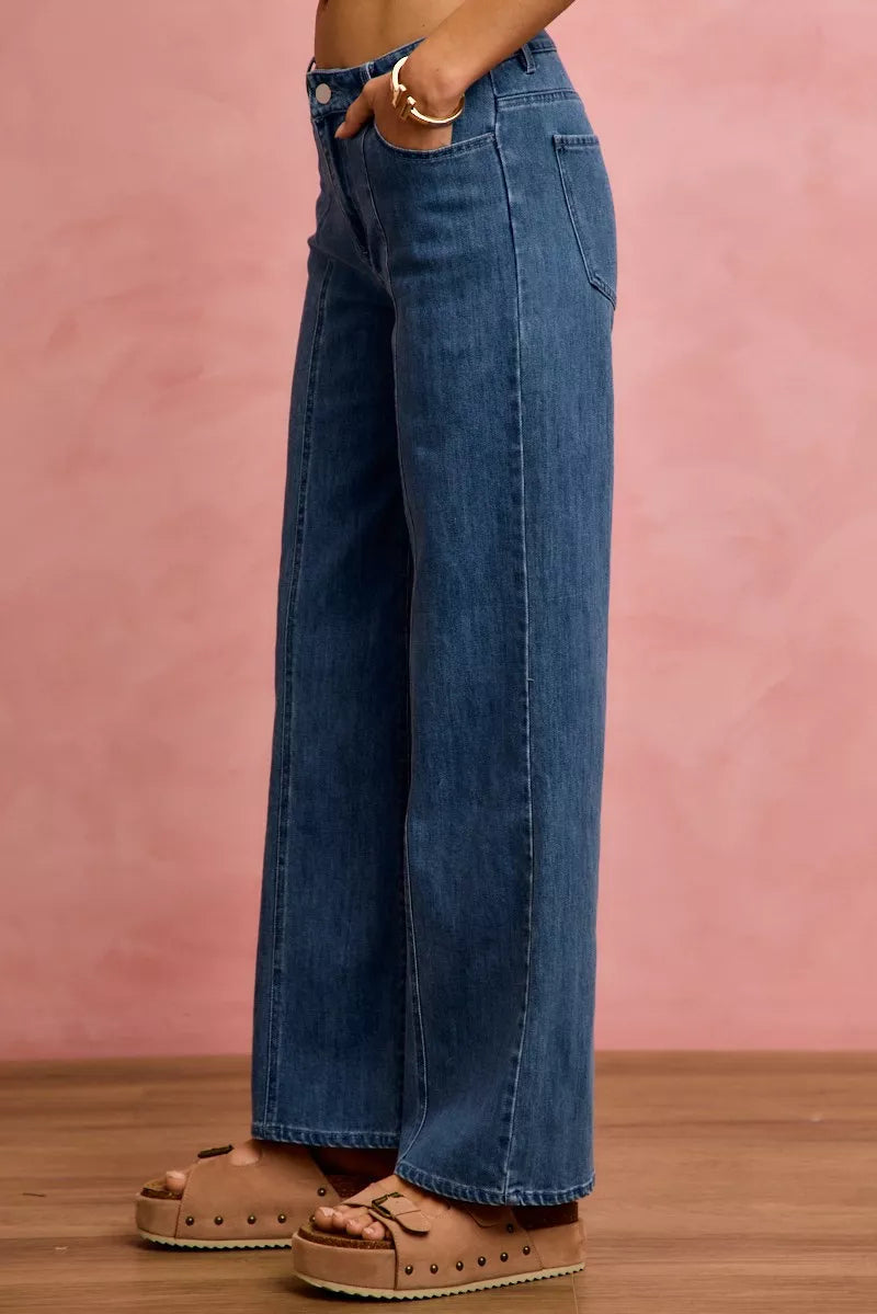 Person wearing blue jeans with a pink background