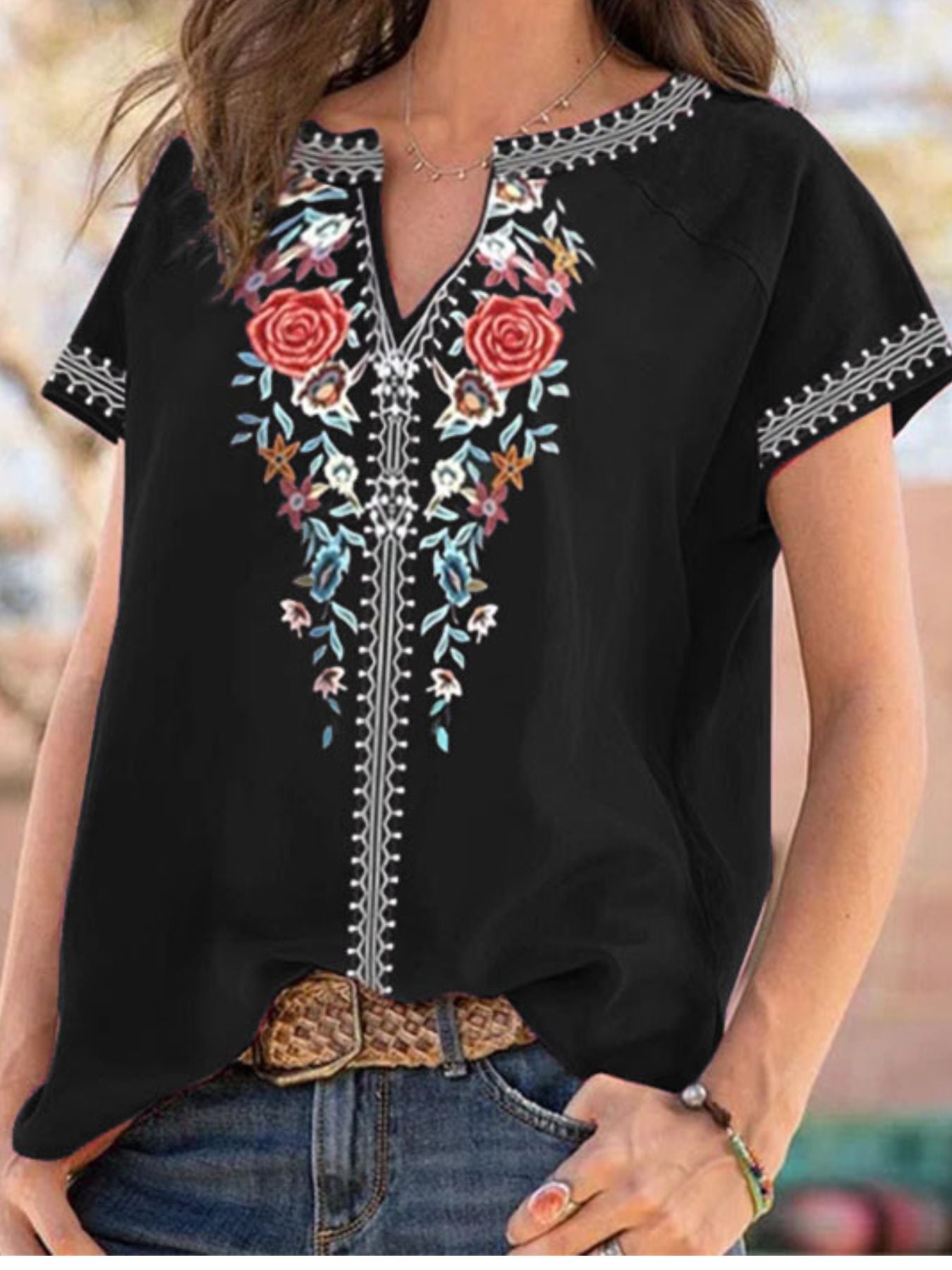 Black blouse with floral embroidery worn by a person outdoors