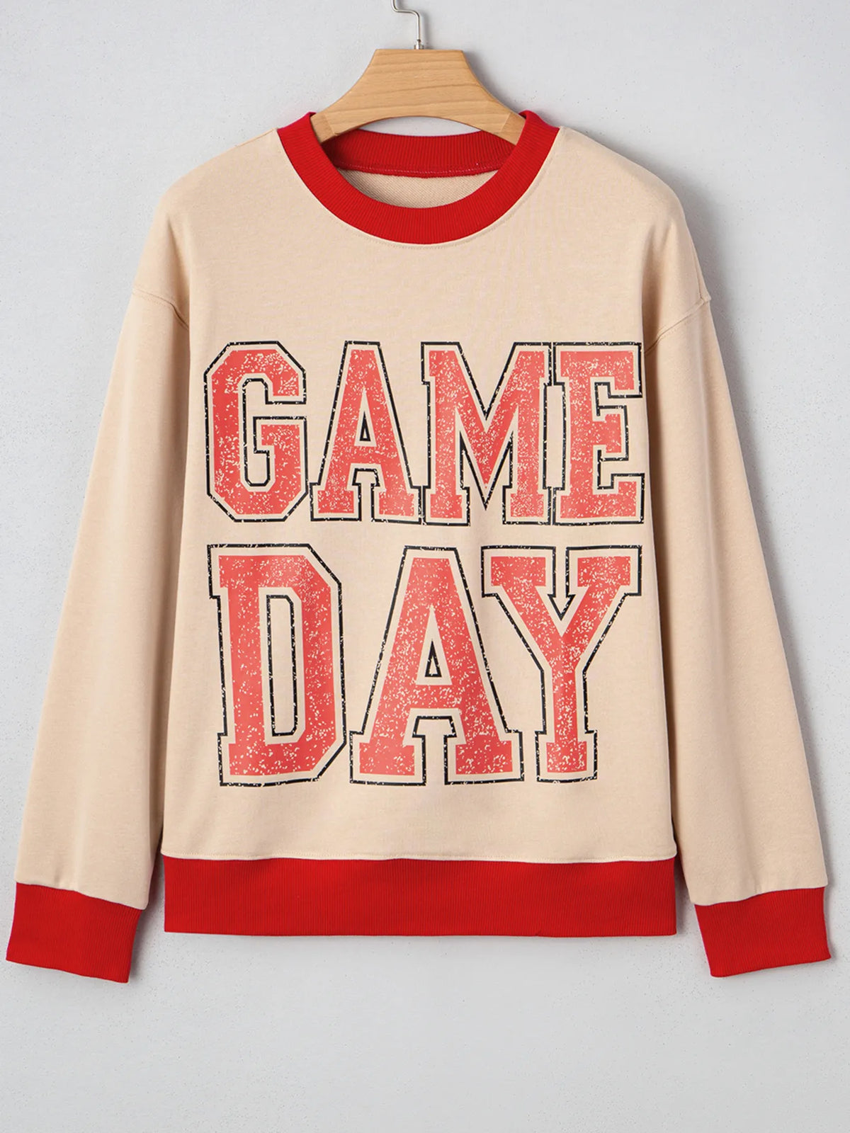 Beige sweatshirt with red 'GAME DAY' text on a hanger against a gray background