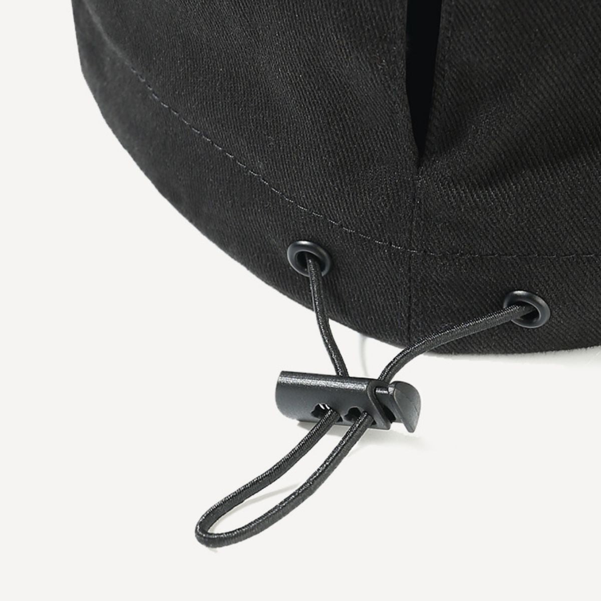 Close-up of a black cap with a chin strap on a white background